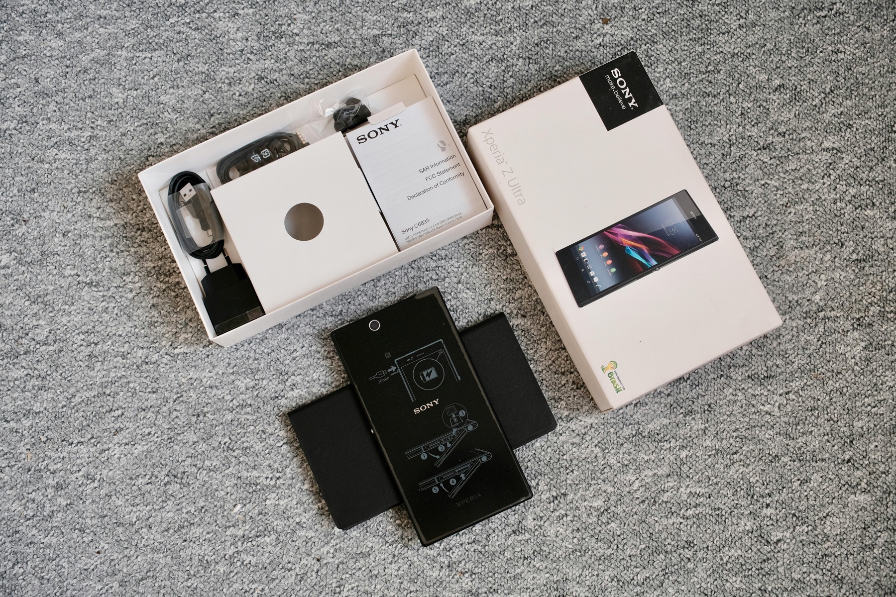 A product unboxing scene with a phone, accessories, and packaging on a table