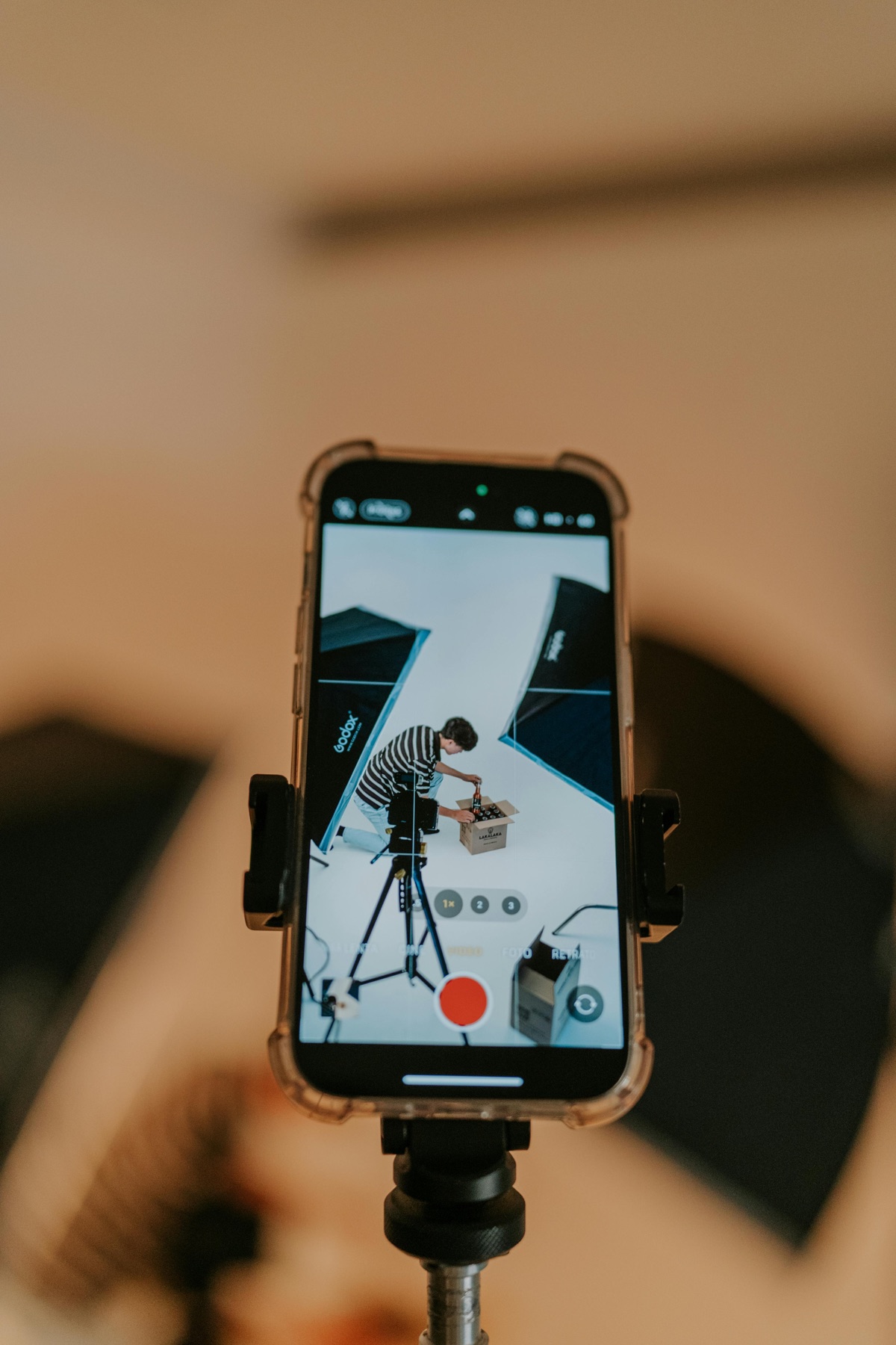 A creator filming an unboxing video with a smartphone in a studio setup